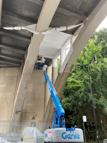 Men painting underside of Dyckman Street Bridge in cherry picker