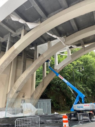 Men painting underside of Dyckman Street Bridge in cherry picker